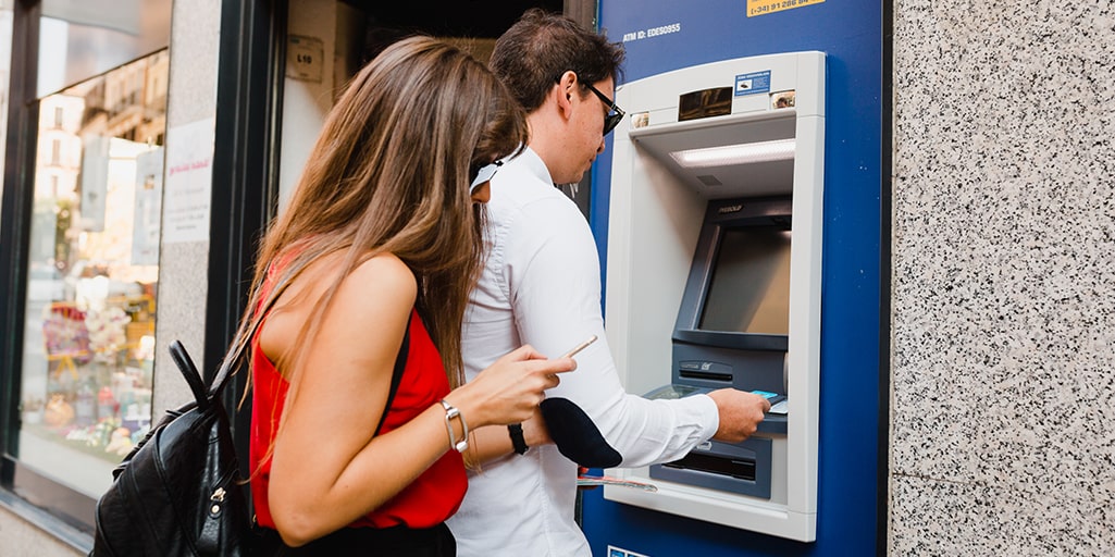 How to save money during your holiday - couple at ATM